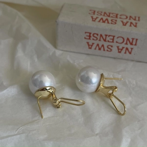 Detailed close-up of 925 silver pearl earrings with golden Omega clip back closure