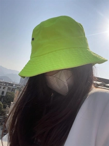 Outdoor close-up of neon green cotton bucket hat with breathable eyelets and stitched brim
