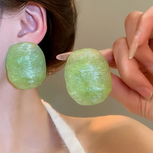 Detailed close-up of oversized light green resin earrings with unique brushed texture