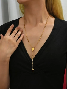 Close-up of a gold rosary necklace with a cross and medallion on a black outfit