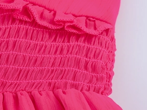 Détail d'une robe en mousseline rose vif avec smocks et bords à volants délicats