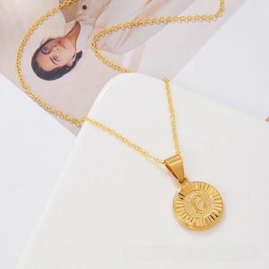 Macro shot of gold circular coin pendant with letter C and radial texture details