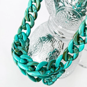 Macro shot of large turquoise and brown marble texture acrylic chain links on glass