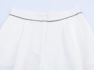 Détail de la taille du pantalon blanc avec surpiqûres noires et texture de tissu lin