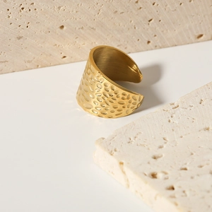 Adjustable golden hammered texture stainless steel open ring on beige travertine stone