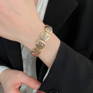 Macro detail of golden metal coin bracelet featuring engraved religious scripture text