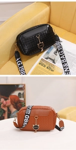 Détail du sac à bandoulière tressé avec breloque chat et large sangle à lettres