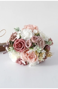 Close-up of bridal faux rose bouquet with pink and white silk flowers and green leaves