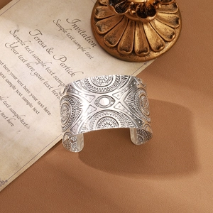Close-up of vintage silver open bangle with embossed geometric sun patterns on leather