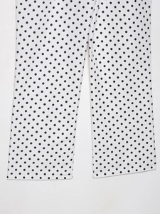 Détail du pantalon blanc à pois noirs montrant la texture tissée et les coutures