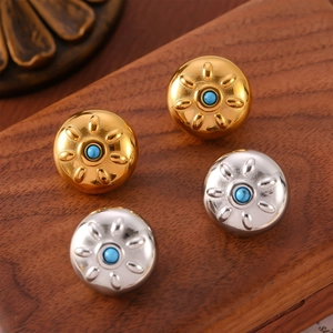 Orecchini a perno sole in oro e argento con perla blu su sfondo di legno scuro