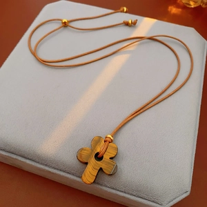 Macro shot of tiger eye stone flower pendant with wax rope on a gray velvet pad