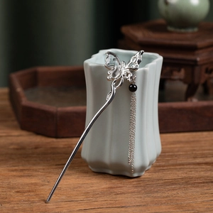 Detailed view of silver butterfly hair pin with metallic fringe and black pearl bead