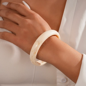 Detailed view of chunky resin round bangle with ivory marble texture on model wrist