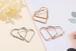 Gros plan détaillé de boucles d'oreilles cœur texturées en or, argent et or rose