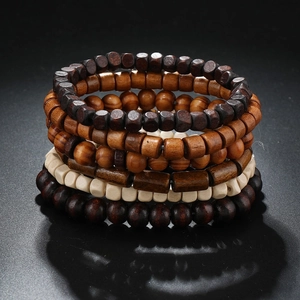 Detailed view of layered wood bead bracelets in deep brown and beige on a dark surface