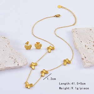 Golden butterfly jewelry set featuring embossed necklace and stud earrings on marble
