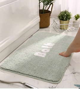 Close-up of mint green bath mat with soft absorbent plush texture and white Bath text