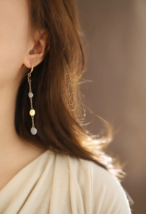 Detail of long fringe earrings with gold and silver round sequins on hanging chains