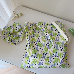 Detailed flat lay of floral cotton tote bag with matching scrunchie and label