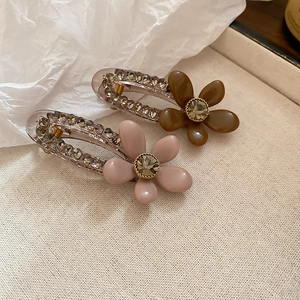 Detailed close-up of acrylic floral hair clips with sparkling rhinestones and faceted gems