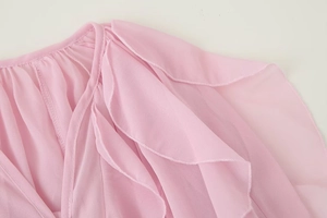 Detailed close-up of layered ruffle texture on a pink V-neck long-sleeve blouse