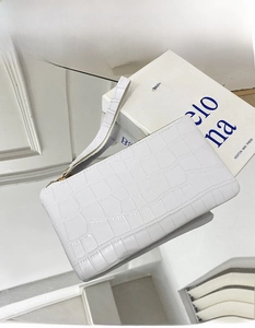 Detail of white crocodile pattern handbag with metal zipper and wrist strap on mirror