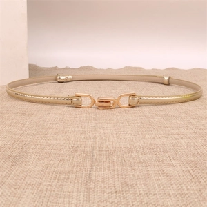 Detail of skinny metallic gold belt with decorative metal interlocking buckle on burlap texture