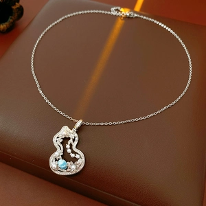 Macro view of silver gourd pendant with white pearls and blue gemstone on leather base