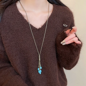 Detail of vintage gold tassel necklace with turquoise beads on a brown sweater
