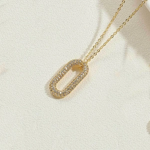 Gros plan d'un collier doré avec pendentif ovale serti de zircons blancs brillants