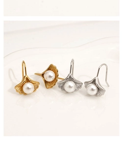 Macro detail of ginkgo leaf earrings with white pearls in gold and silver finishes