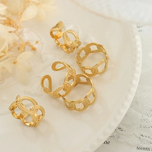 Five gold plated hollow chain link rings displayed on a white ceramic plate