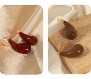 Detailed macro of teardrop earrings with burgundy and brown enamel on silk and stone