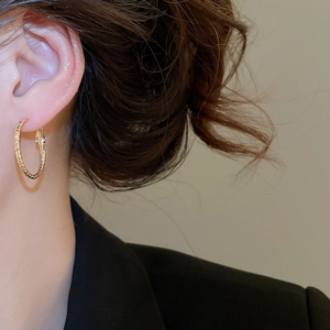 Nahaufnahme eines goldenen strukturierten Creolen-Ohrrings im minimalistischen Stil