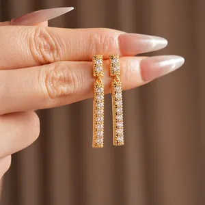 Elegant gold square tassel earrings featuring sparkling cubic zirconia on a dark background