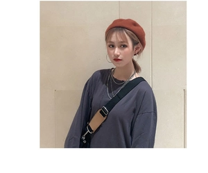 Fashionable caramel wool beret styled with elegant metal earrings and a layered necklace