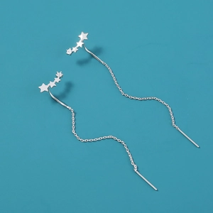 Detail of silver star-shaped long tassel earrings with sparkling zircon on blue background