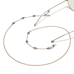 Detailed view of golden metal eyewear chain with blue gemstone beads on white background