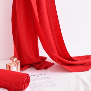 Detailed view of luxury red scarf with fringe tassels on minimalist white background