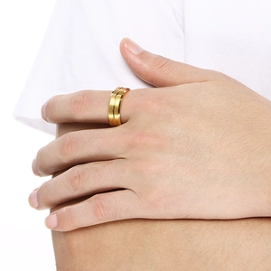 Close-up of a wide brushed gold tungsten ring on a model's hand with a matte finish