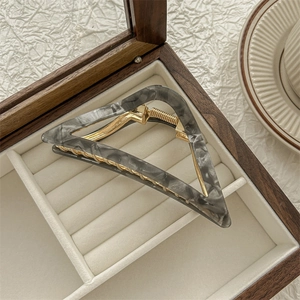 Detailed top view of a triangular grey marble acetate hair claw clip in a jewelry box