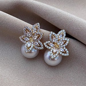 Macro shot of gold flower earrings with pavé zircon petals and round white pearls