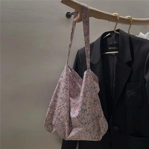 Detail of purple floral cotton tote bag hanging on a wooden hanger over a blazer