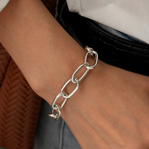 Detail of silver geometric oversized link chain bracelet worn on a female wrist