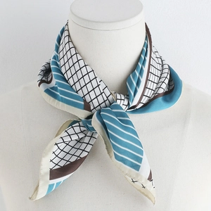 Detailed view of a geometric silk-like scarf with blue and brown patterns on a white base