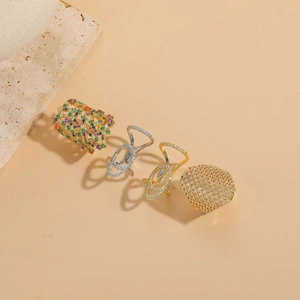 Dettaglio di quattro anelli geometrici in oro e argento con intarsio di zirconi colorati