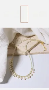 Close-up of elegant freshwater pearl necklace with gold beads on white fabric