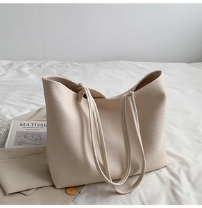 Close-up of cream white tote bag showing soft lychee grain leather and shoulder straps