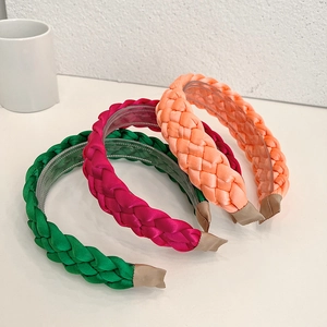 Three braided fabric headbands in green, pink, and orange with satin weave and inner teeth